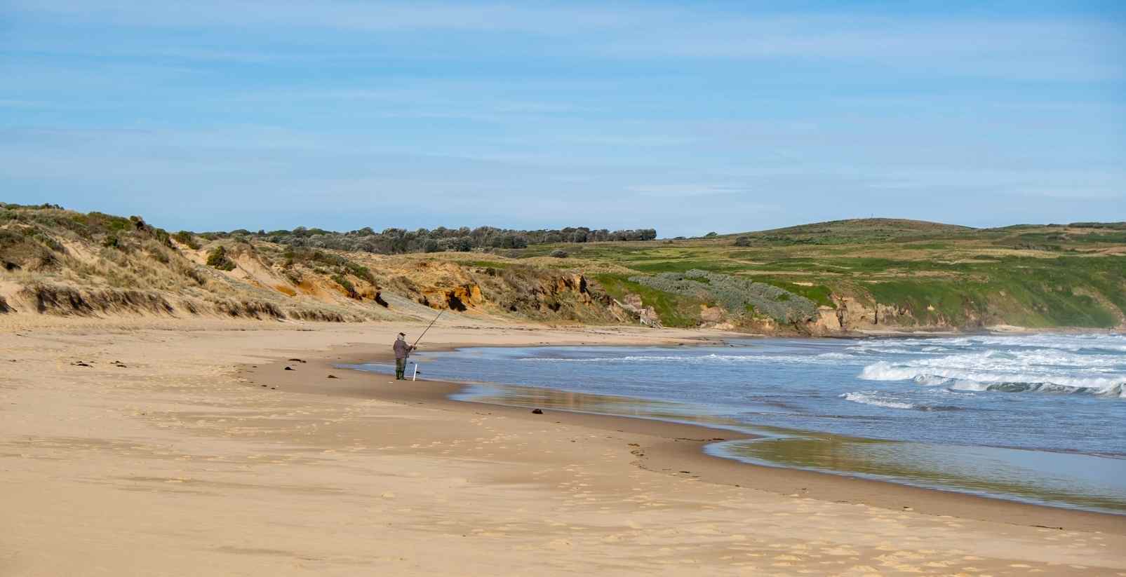 man fishing in distance at cape woolamai beach