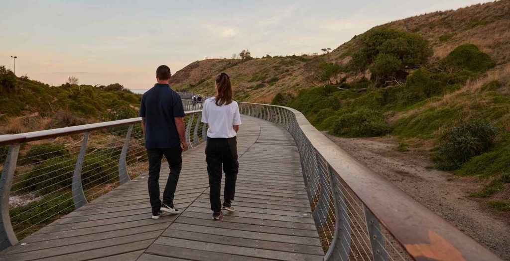 people walking on boardwalk near the penguin parade